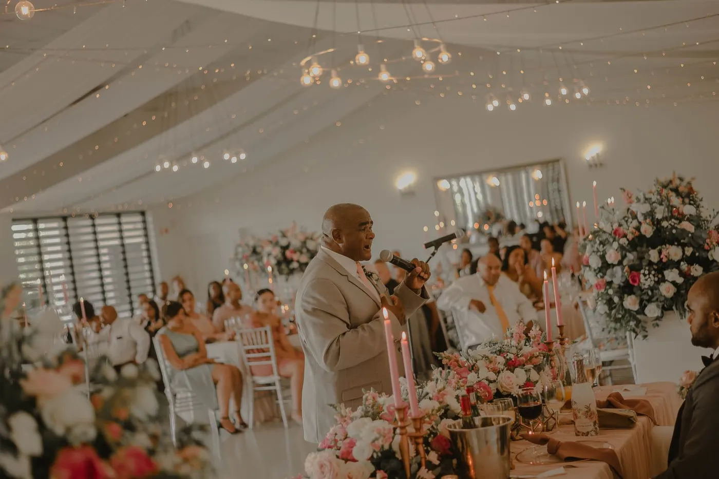 A man giving a speech into a microphone at a wedding reception