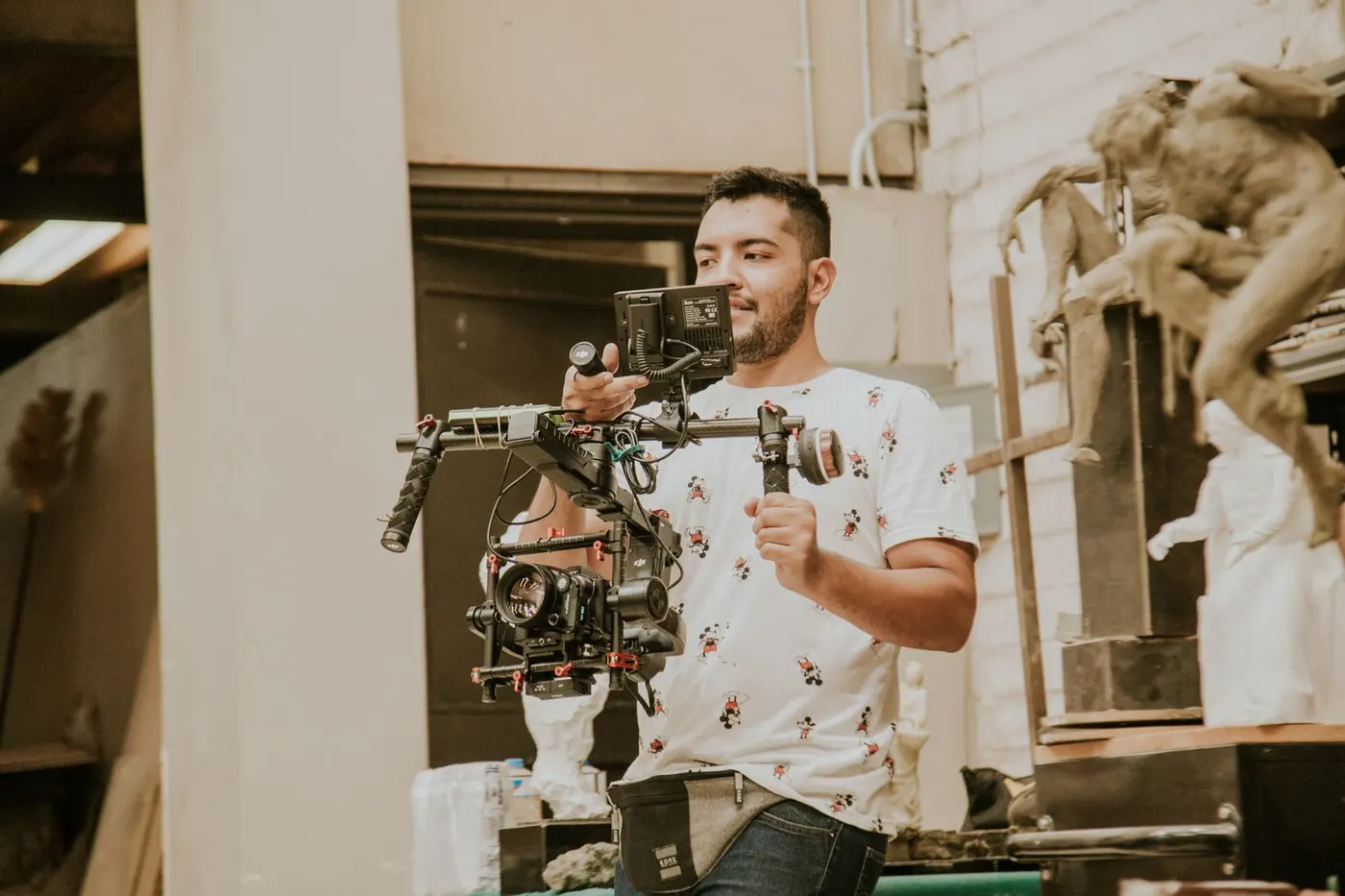 A videographer holding a professional camera on a stabilising rig indoors