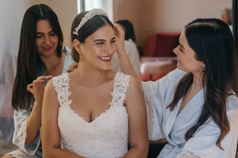 A bride laughing while a friend fixes her hair.