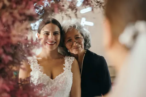 A bride and an older woman smiling cheek to cheek.