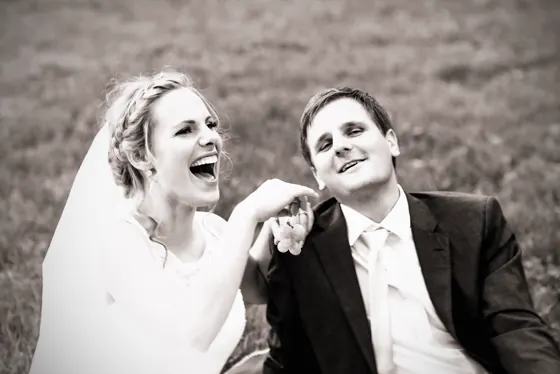 A bride and groom laughing together, in black and white.