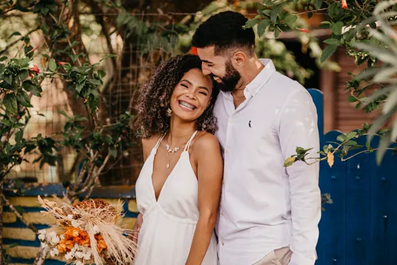 A bride and groom laughing, his head resting against hers.