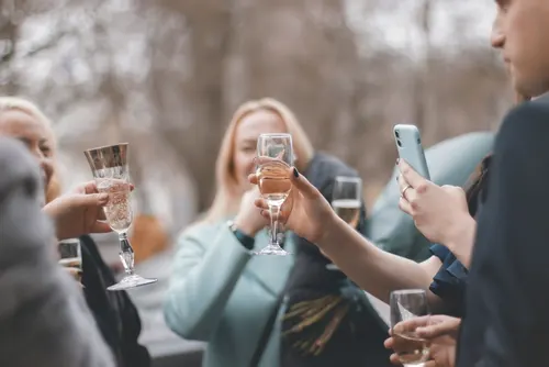 Friends raising a toast while one person captures it on their phone